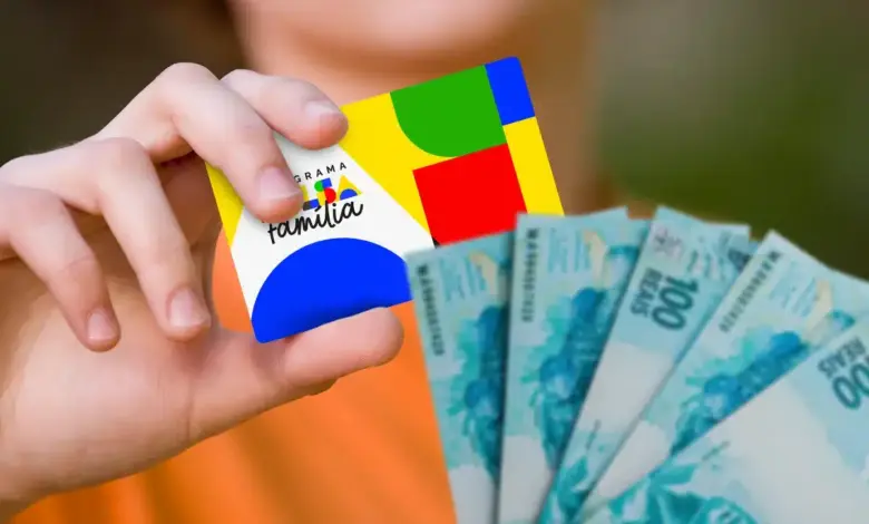 Cartão do Bolsa Família sendo segurado na mão com notas de dinheiro ao lado, representando o pagamento do benefício social.