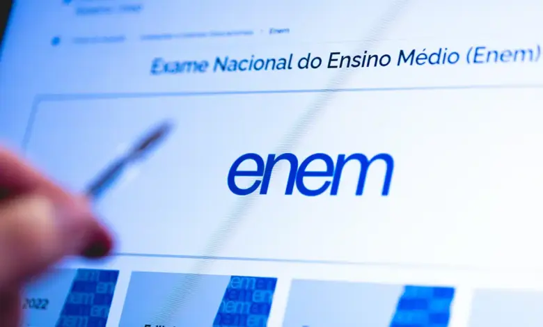 Tela do portal do Enem no Inep com logotipo azul em destaque e mão segurando caneta apontando para informações.
