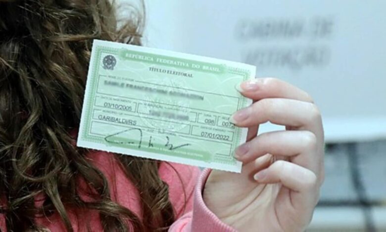 Mulher de cabelos castanhos cacheados segura título eleitoral verde da República Federativa do Brasil.