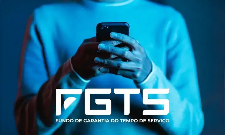 Pessoa segurando smartphone preto com iluminação azul e logo do FGTS - Fundo de Garantia do Tempo de Serviço.