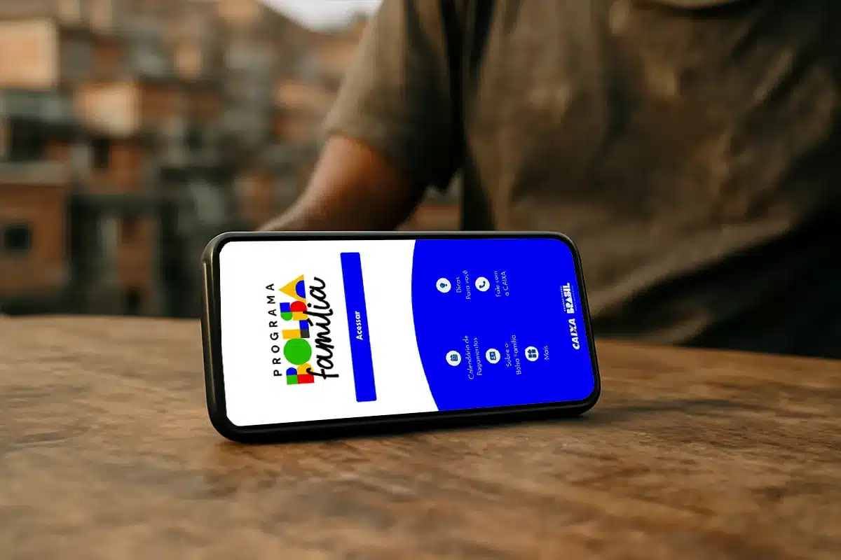 Celular sobre mesa de madeira com a tela do aplicativo Bolsa Família